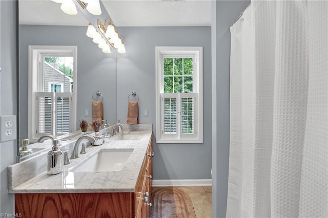 bathroom with plenty of natural light, baseboards, and double vanity