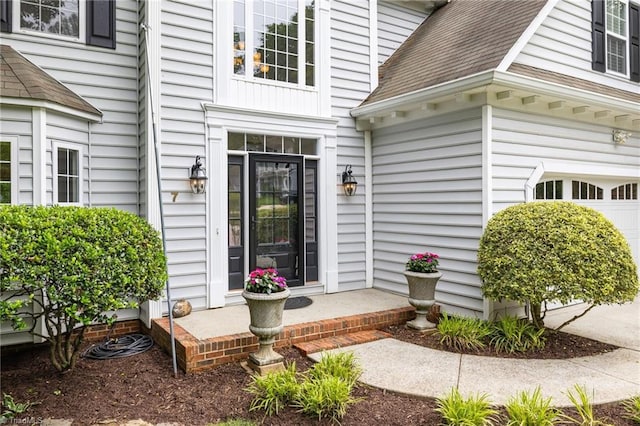 view of exterior entry featuring a shingled roof