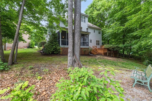 view of green lawn featuring a sunroom and a wooden deck