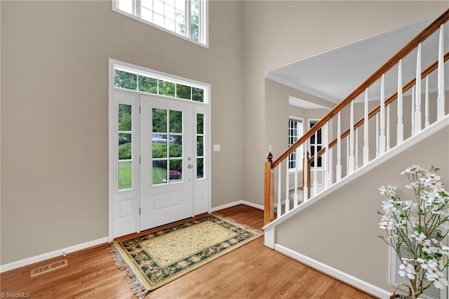 entryway with a high ceiling, wood finished floors, baseboards, and stairway