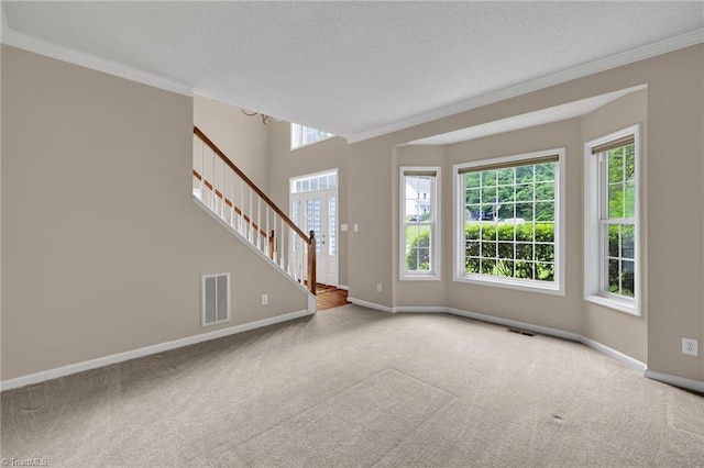 empty room with carpet floors, ornamental molding, stairway, plenty of natural light, and a textured ceiling