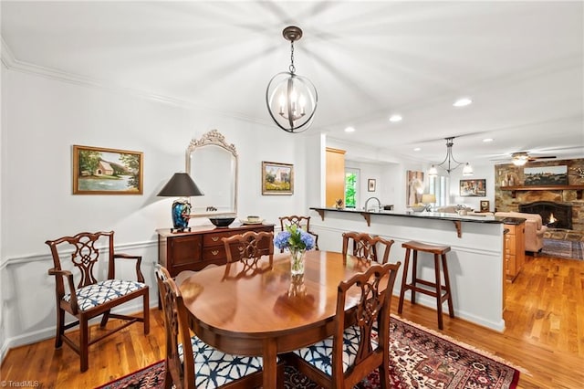 5017 Timbrook Ln, Winston-Salem, NC 27103 - dining space with a chandelier, light wood-type flooring, a stone fireplace, recessed lighting, and crown molding