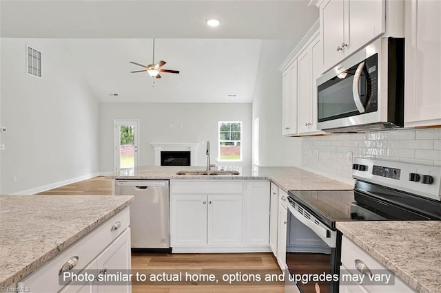 kitchen with appliances with stainless steel finishes, a sink, open floor plan, a ceiling fan, and lofted ceiling