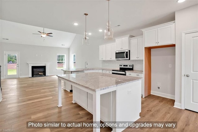 kitchen featuring appliances with stainless steel finishes, white cabinets, a ceiling fan, decorative backsplash, and baseboards