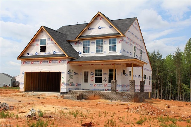 property under construction with covered porch and roof with shingles