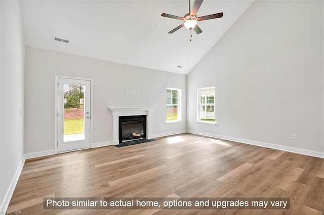 unfurnished living room with light wood-type flooring, high vaulted ceiling, a fireplace with flush hearth, ceiling fan, and baseboards