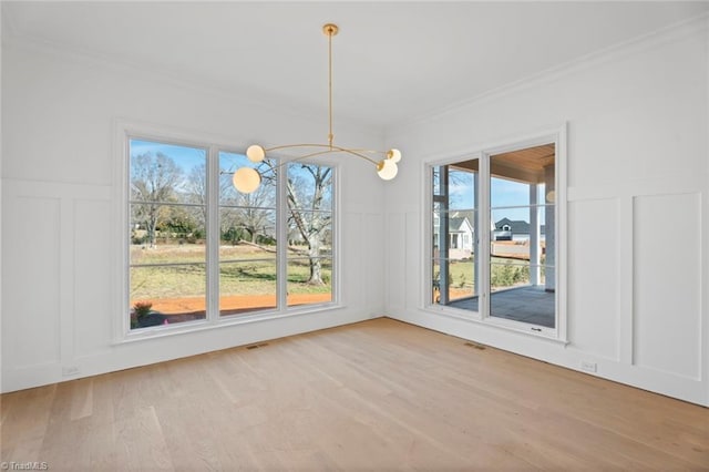 unfurnished dining area featuring hardwood / wood-style flooring, crown molding, and a notable chandelier