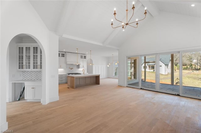 unfurnished living room featuring light hardwood / wood-style floors, an inviting chandelier, and beam ceiling