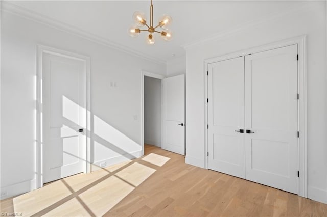 unfurnished bedroom featuring light wood-type flooring, ornamental molding, a notable chandelier, and a closet