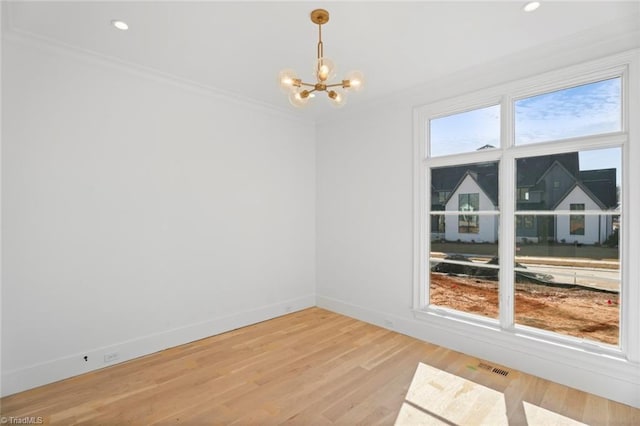 empty room featuring crown molding, a notable chandelier, and hardwood / wood-style flooring