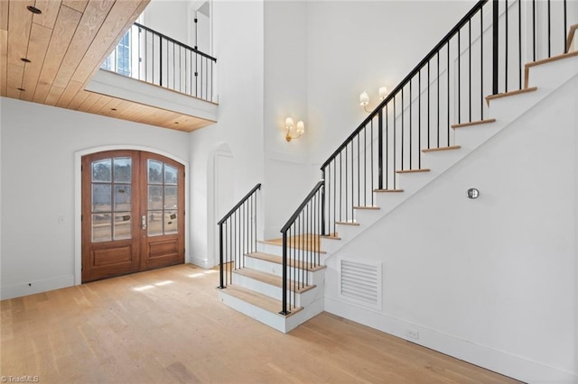 foyer featuring wood-type flooring, a towering ceiling, wood ceiling, and french doors