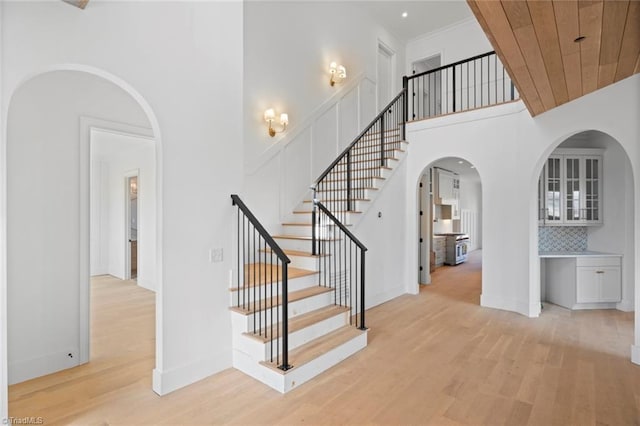 staircase with hardwood / wood-style floors, wood ceiling, and a high ceiling