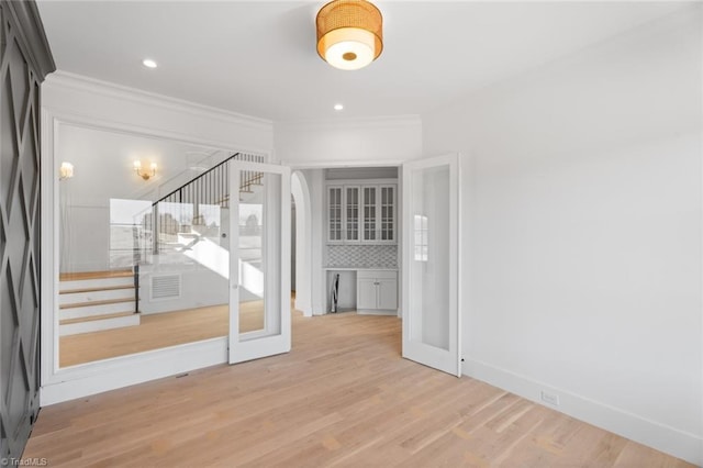 empty room featuring french doors, ornamental molding, and wood-type flooring