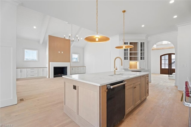 kitchen with light wood-type flooring, a kitchen island with sink, hanging light fixtures, sink, and dishwasher