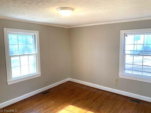 spare room featuring a textured ceiling, a healthy amount of sunlight, wood-type flooring, and ornamental molding