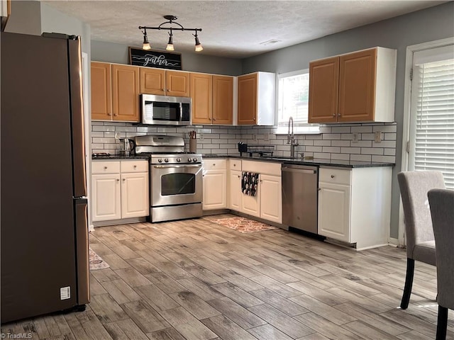 5227 Eagle Creek Dr, Charlotte, NC 28269 - kitchen featuring stainless steel appliances, dark countertops, a sink, backsplash, and light wood finished floors