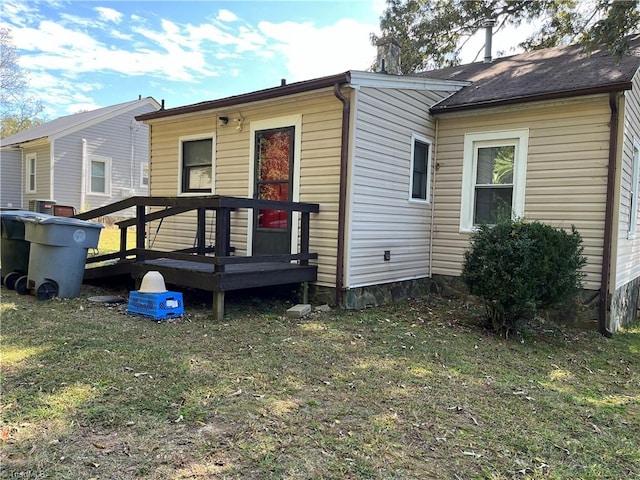 rear view of house with a deck and a yard