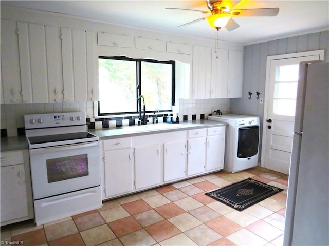 kitchen with washer / dryer, white appliances, light tile patterned floors, white cabinets, and sink