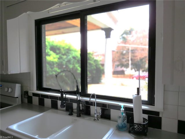 details with sink, white cabinets, and decorative backsplash