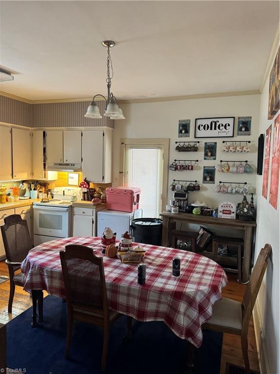 dining area with crown molding, an inviting chandelier, and hardwood / wood-style flooring