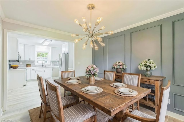 dining room featuring a chandelier, a decorative wall, light wood-style floors, and crown molding
