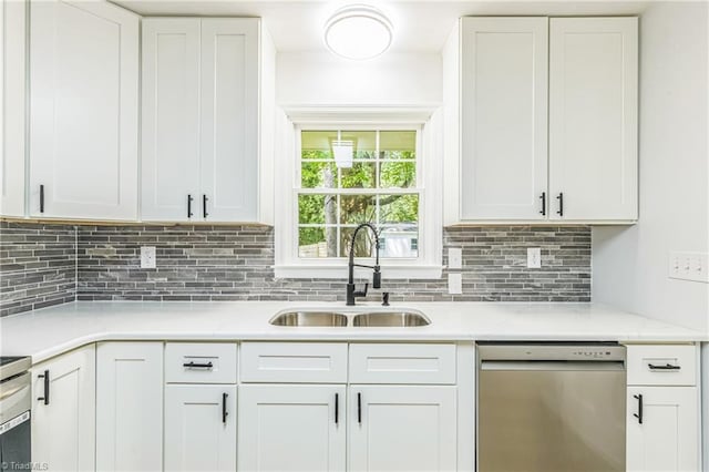 kitchen featuring stainless steel dishwasher, a sink, decorative backsplash, white cabinets, and light stone counters