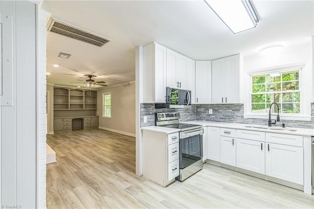 kitchen with appliances with stainless steel finishes, a sink, light countertops, and light wood finished floors