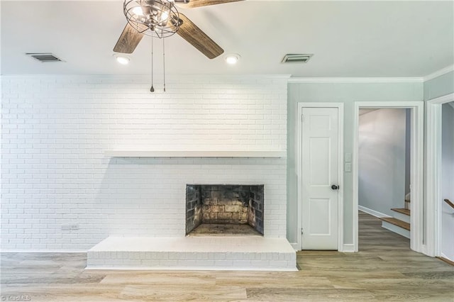 detailed view of a ceiling fan, crown molding, wood finished floors, a fireplace, and brick wall