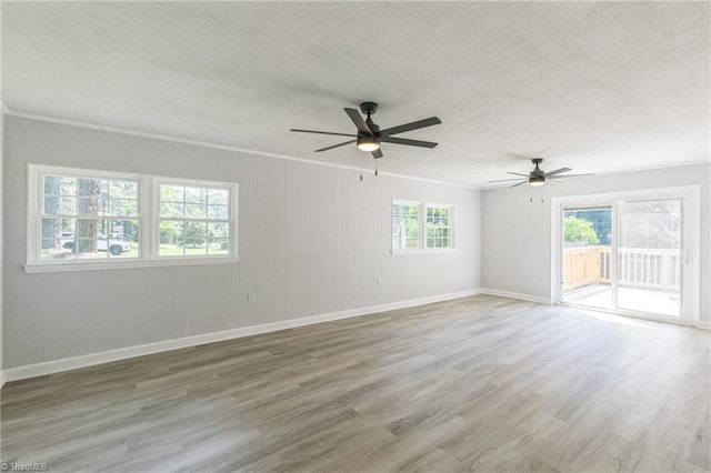 unfurnished room featuring healthy amount of natural light, wood finished floors, ceiling fan, a textured ceiling, and ornamental molding