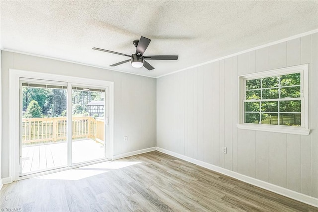 spare room with wood finished floors, a textured ceiling, ceiling fan, baseboards, and ornamental molding