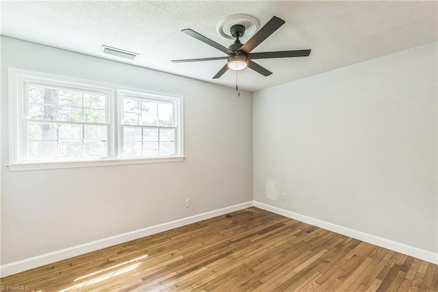 unfurnished room with ceiling fan, wood finished floors, baseboards, and a textured ceiling