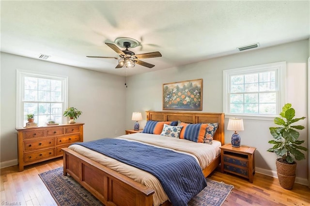 bedroom featuring multiple windows, light wood finished floors, baseboards, and a ceiling fan