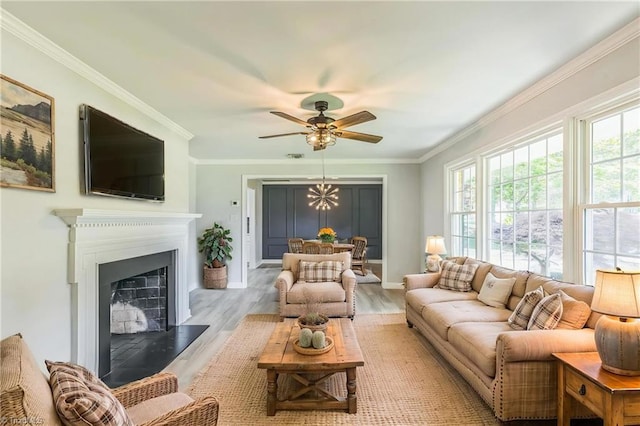 living room featuring wood finished floors, ornamental molding, ceiling fan, a fireplace with raised hearth, and baseboards