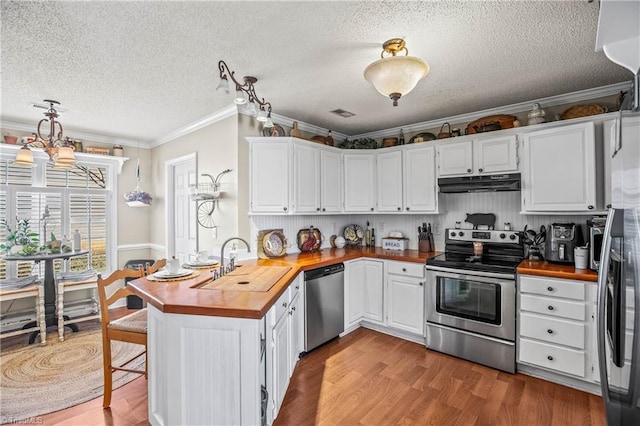 kitchen featuring wood counters, sink, kitchen peninsula, stainless steel appliances, and white cabinets