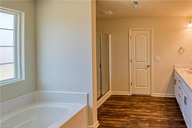 bathroom featuring vanity, hardwood / wood-style floors, and plus walk in shower