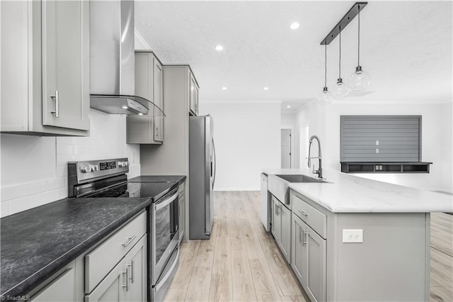 kitchen featuring pendant lighting, gray cabinets, stainless steel appliances, an island with sink, and wall chimney exhaust hood