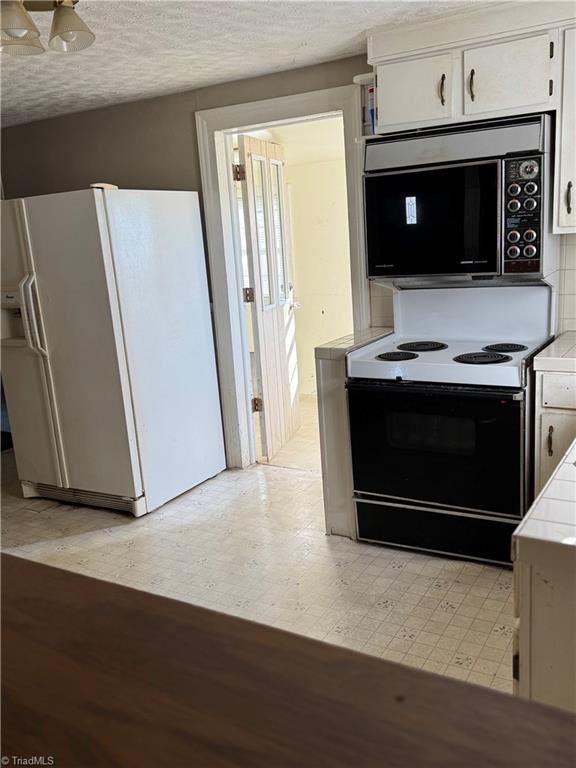 kitchen featuring white cabinets, white appliances, tile countertops, and backsplash