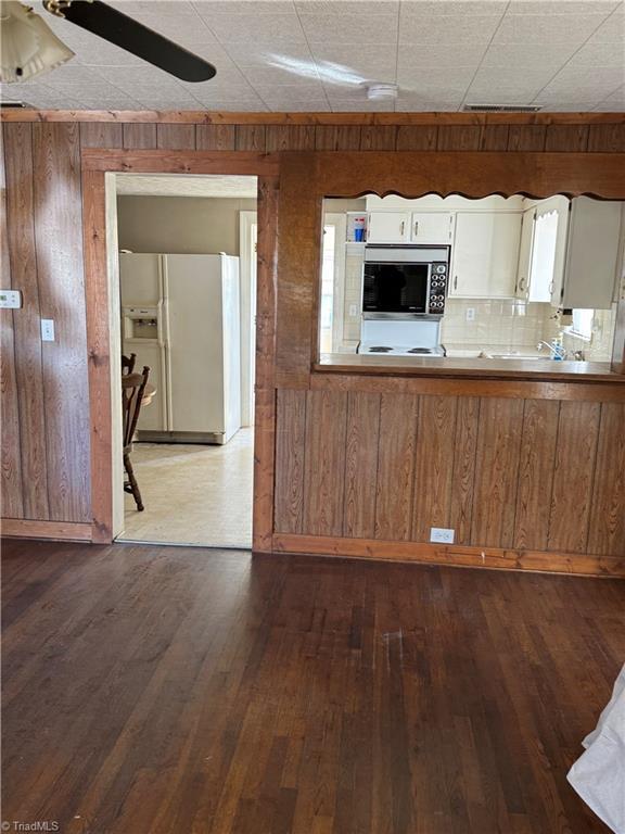 kitchen with white cabinets, dark hardwood / wood-style flooring, white fridge with ice dispenser, and built in microwave