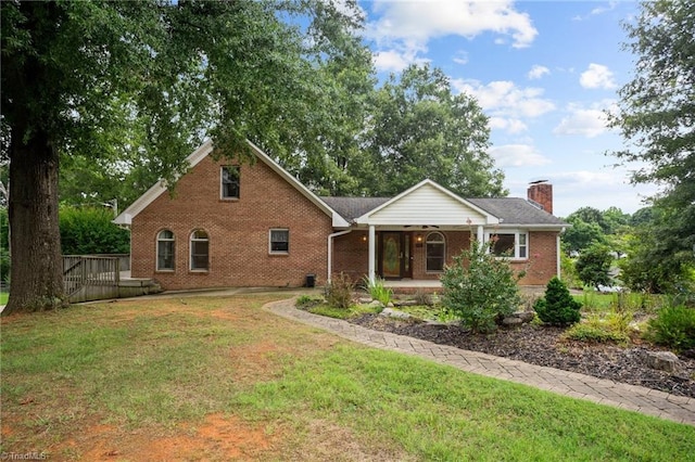 view of front of house with a porch, brick siding, a chimney, and a front yard