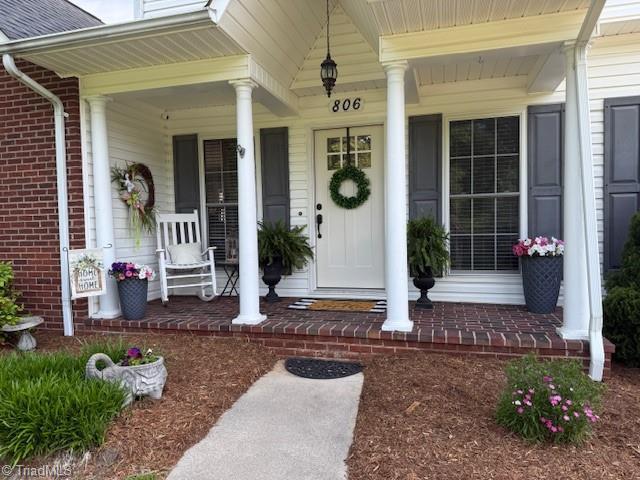 entrance to property featuring covered porch and brick siding