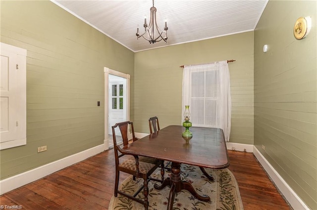 dining space with an inviting chandelier, crown molding, and dark wood-type flooring