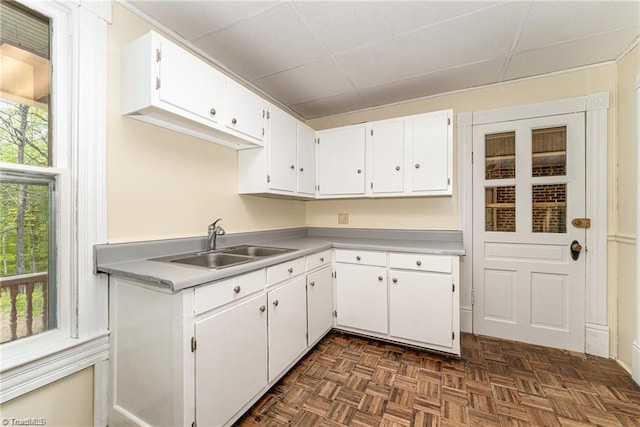 kitchen featuring white cabinetry, dark parquet flooring, and sink