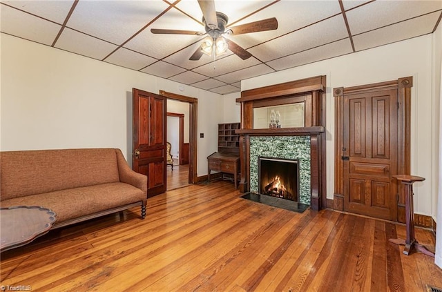 living room with ceiling fan, hardwood / wood-style flooring, and a drop ceiling