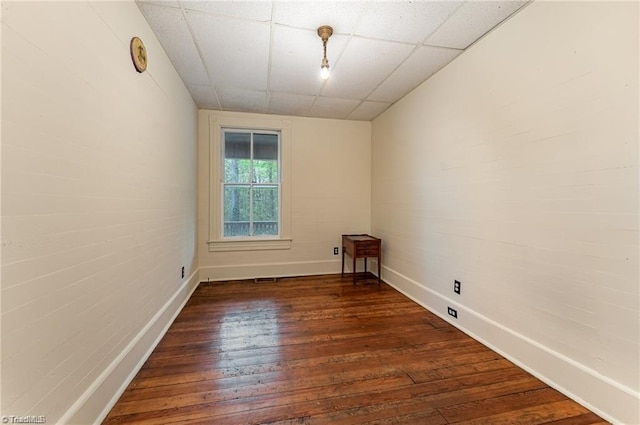 unfurnished room featuring a paneled ceiling and dark hardwood / wood-style floors