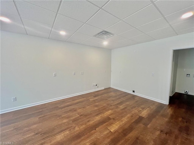 empty room with a drop ceiling and dark hardwood / wood-style floors