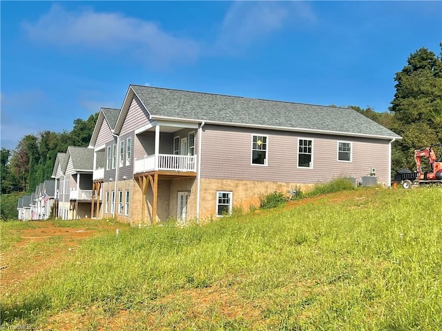 back of property featuring a balcony and central AC