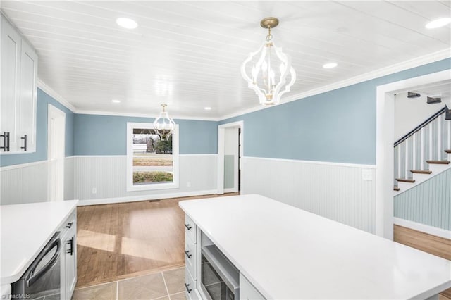 kitchen featuring light countertops, wainscoting, white cabinets, and built in microwave