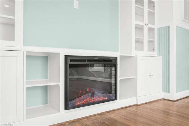 details featuring a warm lit fireplace and wood finished floors