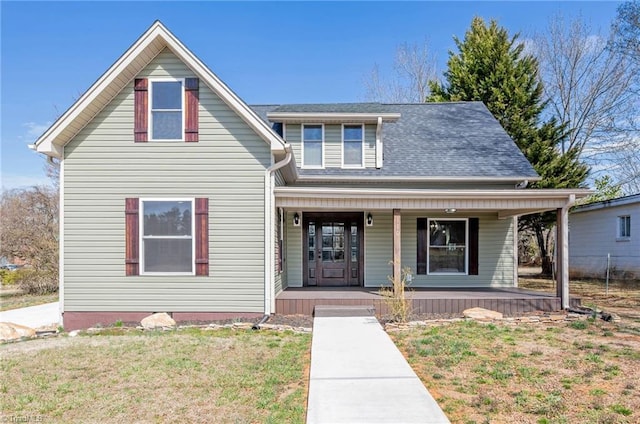 traditional home with covered porch, a front lawn, and roof with shingles