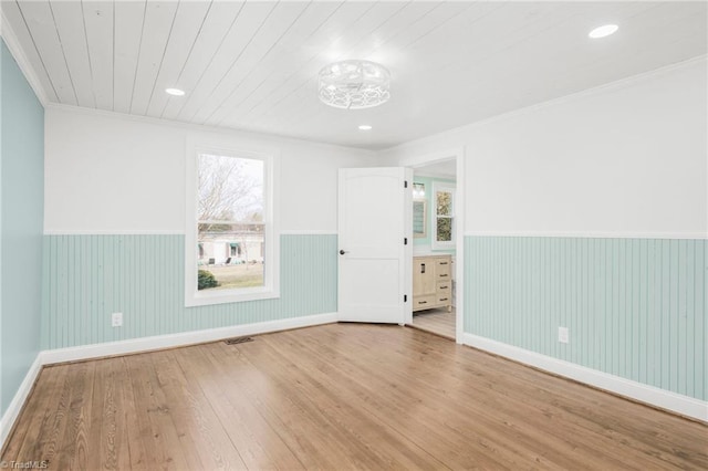 spare room featuring a wainscoted wall, wood finished floors, wood ceiling, and crown molding